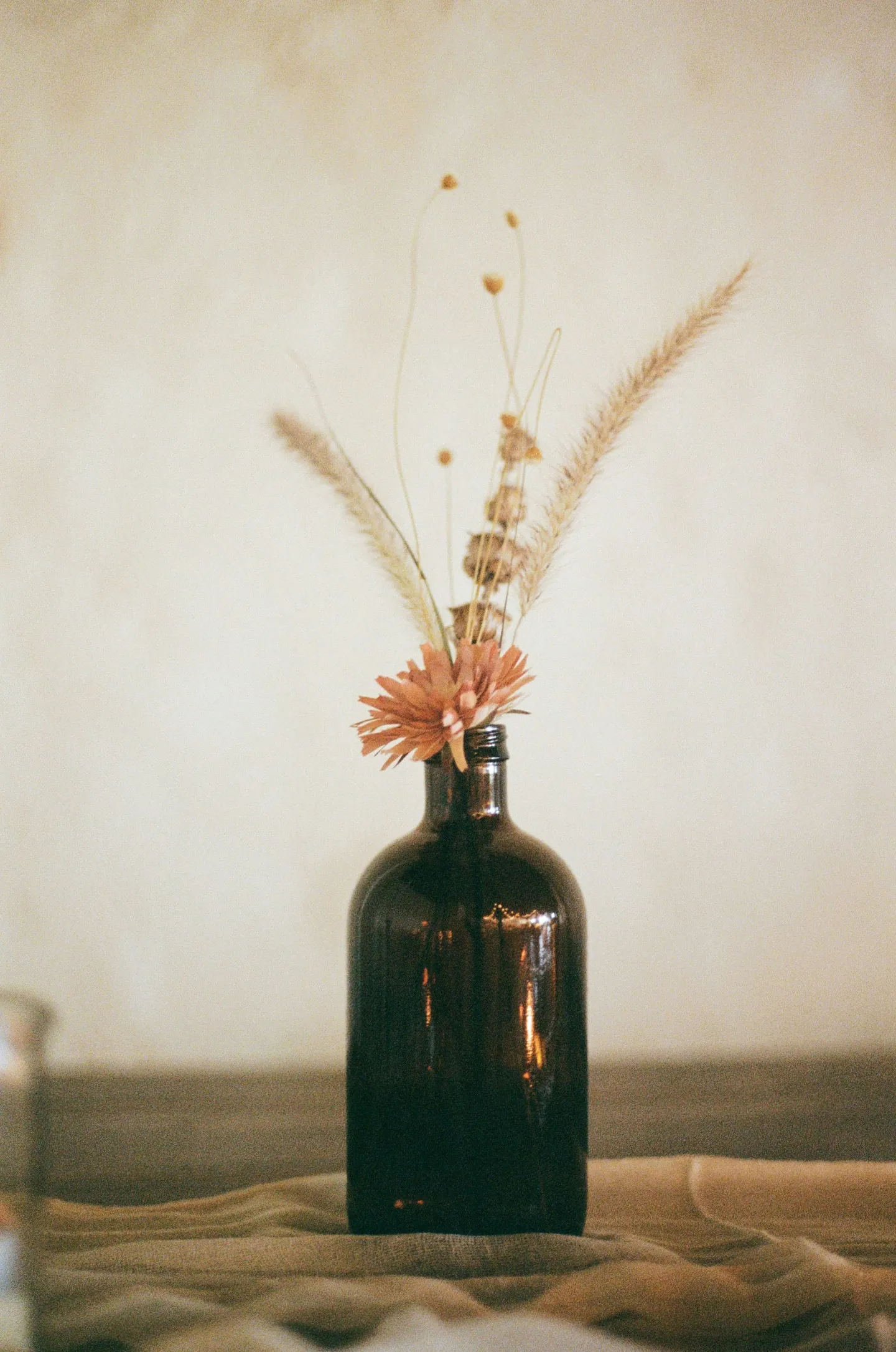Flacon sombre accompagné de fleurs blanches